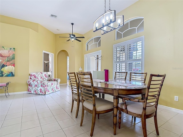 dining area featuring arched walkways, baseboards, a towering ceiling, ceiling fan, and light tile patterned flooring