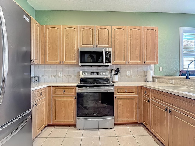 kitchen featuring stainless steel appliances, light tile patterned floors, decorative backsplash, light countertops, and light brown cabinets