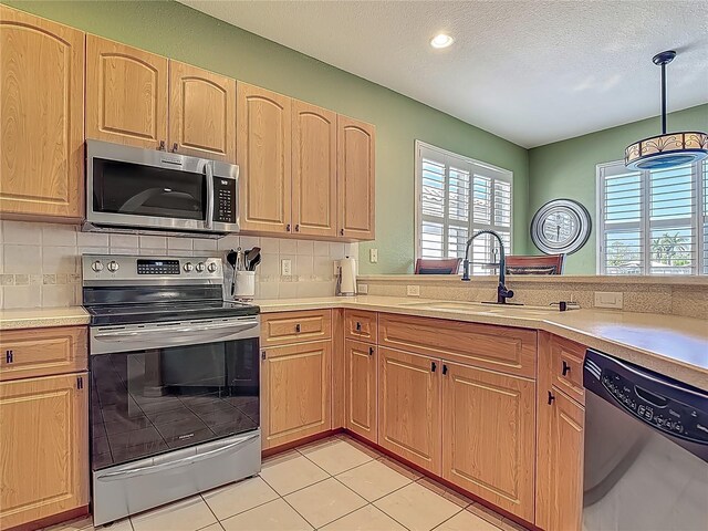 kitchen with stainless steel appliances, a sink, light countertops, backsplash, and a textured ceiling