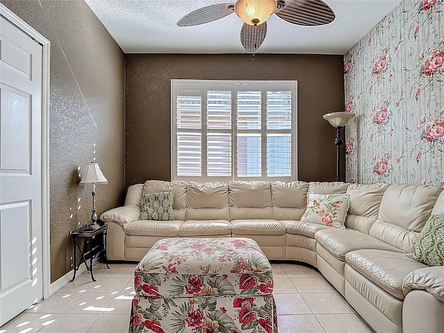 living area with a textured wall, a ceiling fan, light tile patterned floors, and a textured ceiling