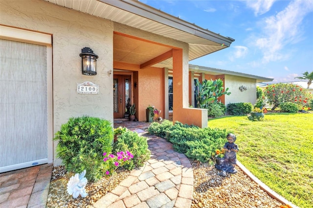 doorway to property featuring stucco siding, a yard, and a porch