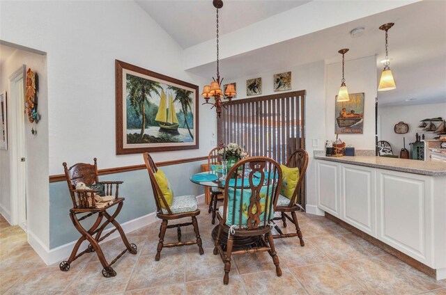 dining area with a chandelier, vaulted ceiling, light tile patterned flooring, and baseboards