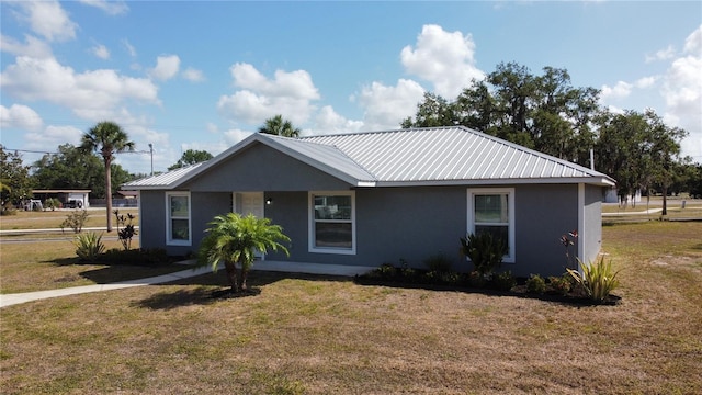 single story home featuring stucco siding, metal roof, and a front yard