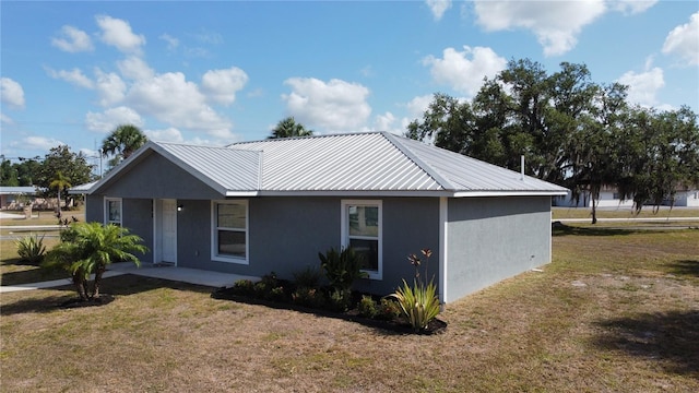 view of side of property with a yard, metal roof, and stucco siding