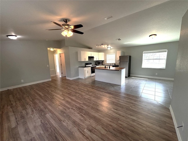 kitchen with freestanding refrigerator, lofted ceiling, open floor plan, and electric stove