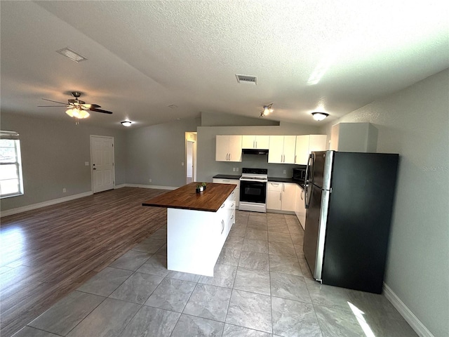 kitchen with freestanding refrigerator, lofted ceiling, a center island, electric range oven, and wood counters