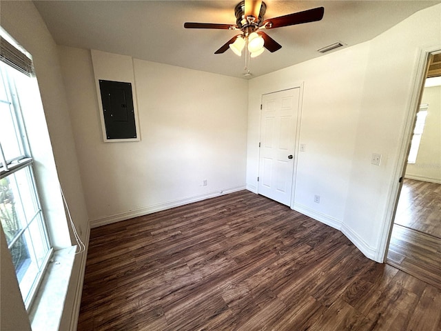 unfurnished bedroom featuring electric panel, visible vents, a ceiling fan, dark wood-style floors, and baseboards