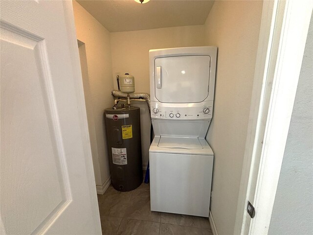 laundry area featuring electric water heater, stacked washer and dryer, and tile patterned floors