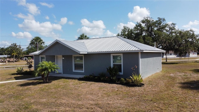 ranch-style home featuring a front lawn, stucco siding, metal roof, and a porch