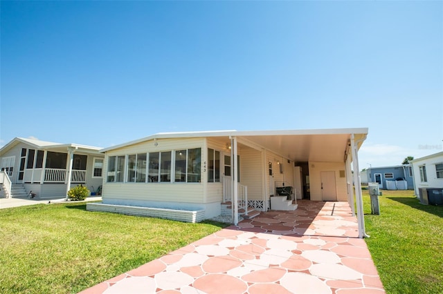 643 Blackburn Blvd, North Port, FL 34287 - view of front of house featuring a sunroom, entry steps, a carport, a front lawn, and driveway