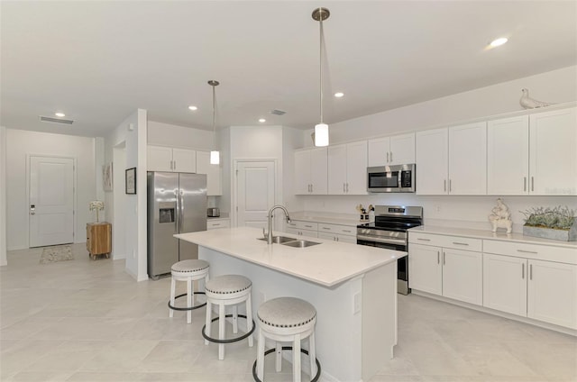 10995 Pinot Dr, Venice, FL 34293 - kitchen featuring a kitchen bar, an island with sink, a sink, stainless steel appliances, and white cabinets