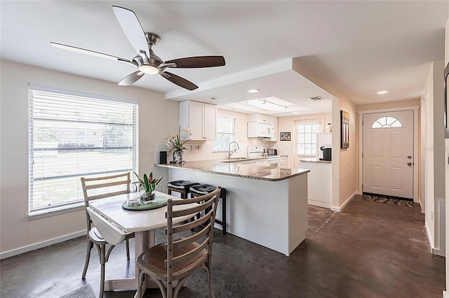 320 W Ann St, Punta Gorda, FL 33950 - kitchen featuring a peninsula, white appliances, concrete flooring, white cabinetry, and baseboards