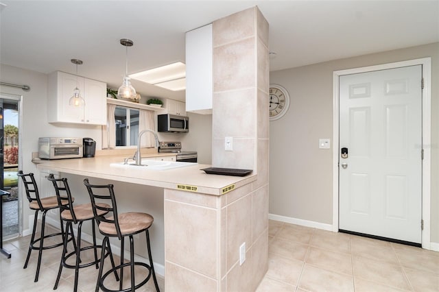 2331 Cannolot Blvd, Port Charlotte, FL 33948 - kitchen with a sink, appliances with stainless steel finishes, a breakfast bar, light countertops, and light tile patterned floors