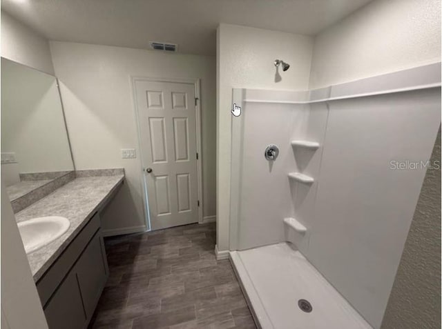 full bathroom featuring a shower, vanity, wood finished floors, and baseboards
