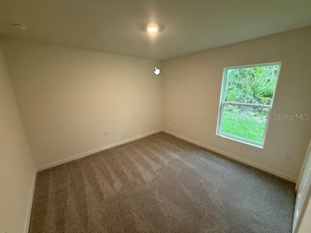 carpeted spare room featuring baseboards