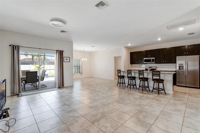 1443 SW 1st St, Cape Coral, FL 33991 - kitchen featuring appliances with stainless steel finishes, open floor plan, a chandelier, a kitchen bar, and decorative backsplash