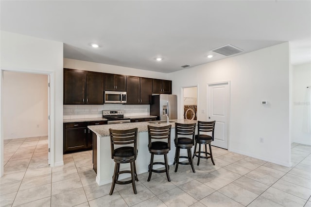 1443 SW 1st St, Cape Coral, FL 33991 - kitchen with stainless steel appliances, light tile patterned floors, a kitchen bar, an island with sink, and recessed lighting