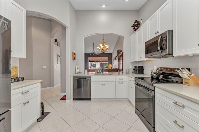 kitchen featuring light tile patterned floors, a notable chandelier, arched walkways, light countertops, and appliances with stainless steel finishes