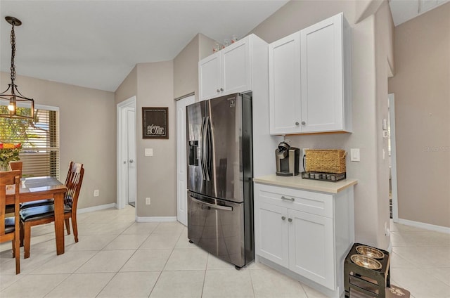 kitchen featuring light tile patterned floors, stainless steel fridge, white cabinets, light countertops, and lofted ceiling