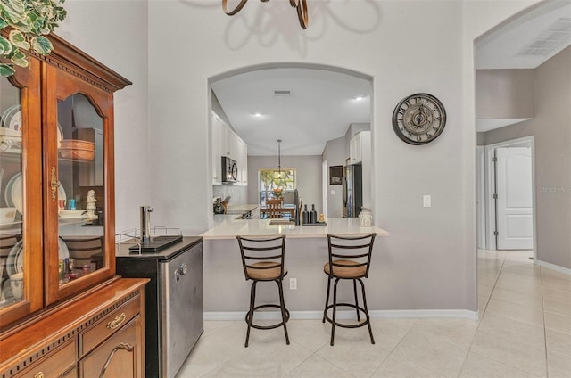 bar with light tile patterned floors, stainless steel appliances, visible vents, arched walkways, and a chandelier