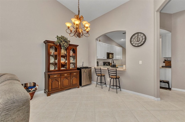 dining area featuring a notable chandelier, baseboards, light tile patterned flooring, high vaulted ceiling, and arched walkways