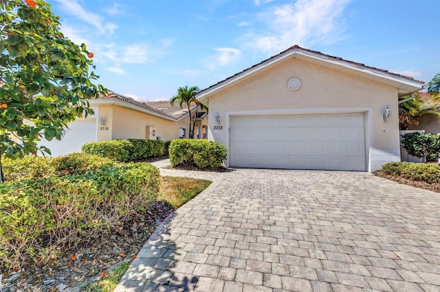 ranch-style house with stucco siding, decorative driveway, and a garage