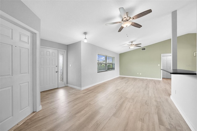 foyer with ceiling fan, light wood-style flooring, lofted ceiling, and baseboards