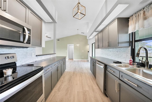 kitchen with stainless steel appliances, vaulted ceiling, light wood finished floors, decorative light fixtures, and tasteful backsplash