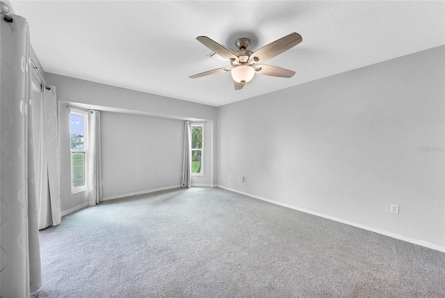 empty room with ceiling fan, carpet flooring, baseboards, and a textured ceiling