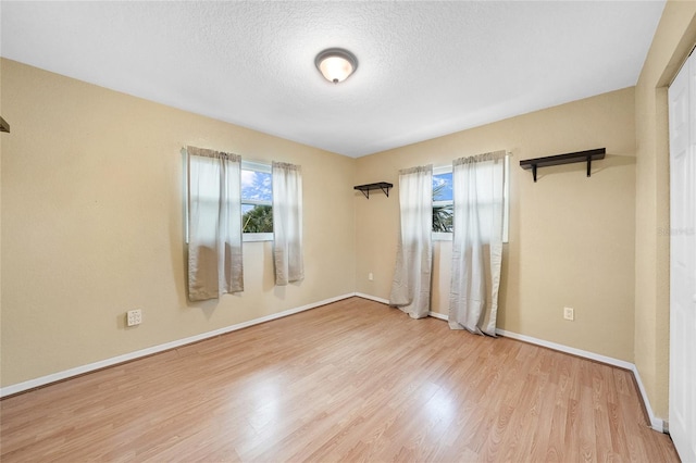 spare room with wood finished floors, baseboards, and a textured ceiling