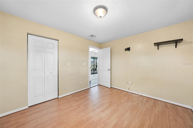 unfurnished bedroom with light wood-style floors, baseboards, a closet, and a textured ceiling