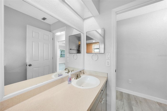 bathroom with wood finished floors, vanity, and baseboards
