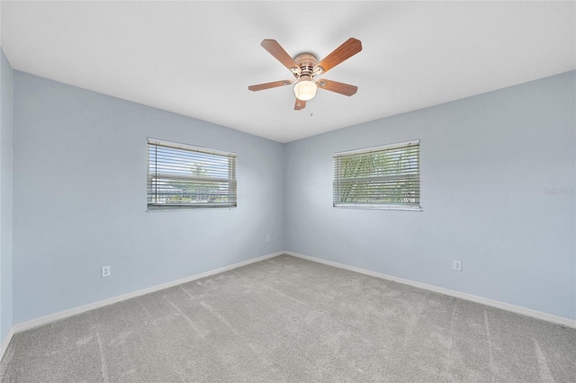carpeted spare room with a ceiling fan and baseboards