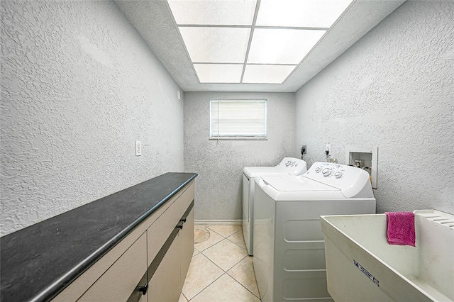 laundry area with a textured wall, washing machine and clothes dryer, and light tile patterned flooring