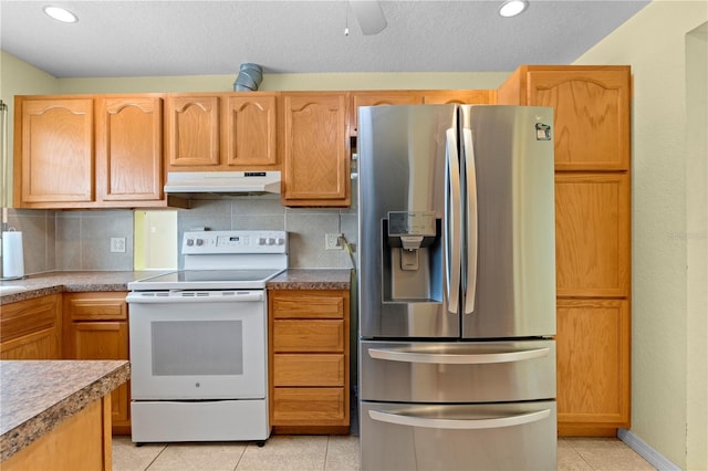5527 Fairway Dr S, Punta Gorda, FL 33982 - kitchen with stainless steel refrigerator with ice dispenser, white electric range oven, under cabinet range hood, light tile patterned floors, and decorative backsplash