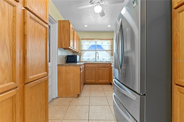 5527 Fairway Dr S, Punta Gorda, FL 33982 - kitchen with freestanding refrigerator, a textured ceiling, light tile patterned flooring, ceiling fan, and brown cabinets