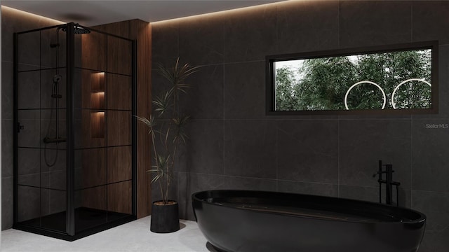 full bathroom featuring tile walls, a shower stall, and a freestanding bath