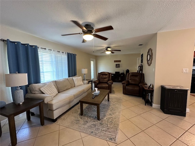 living area featuring light tile patterned floors, ceiling fan, and a textured ceiling