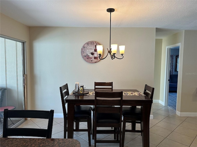 dining space with an inviting chandelier, light tile patterned floors, baseboards, and a textured ceiling