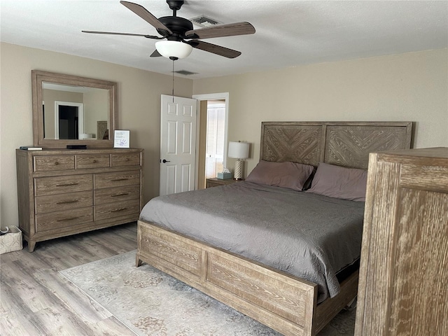 bedroom with light wood finished floors, visible vents, and ceiling fan