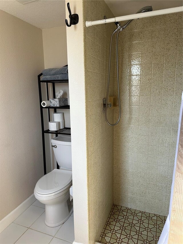 bathroom featuring a shower stall, tile patterned flooring, and toilet