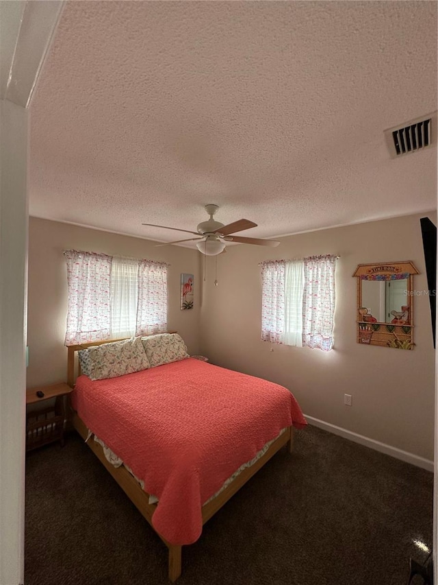 bedroom featuring multiple windows, a textured ceiling, visible vents, and a ceiling fan