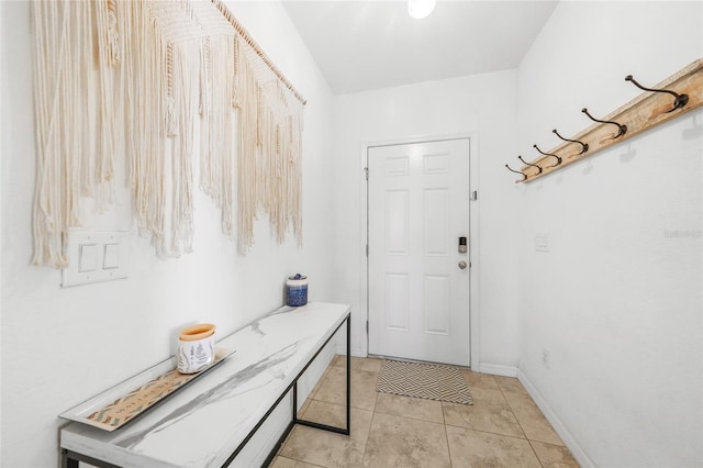 doorway featuring baseboards and light tile patterned floors