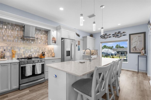 2911 Riverside Dr, Punta Gorda, FL 33950 - kitchen featuring appliances with stainless steel finishes, wall chimney exhaust hood, backsplash, a sink, and light wood-style floors