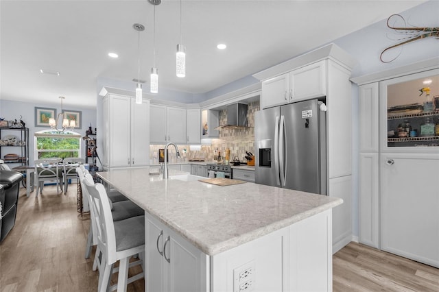 2911 Riverside Dr, Punta Gorda, FL 33950 - kitchen featuring stainless steel appliances, a sink, light wood finished floors, wall chimney exhaust hood, and white cabinets