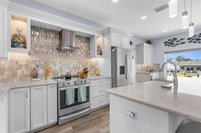 2911 Riverside Dr, Punta Gorda, FL 33950 - kitchen featuring stainless steel appliances, wall chimney exhaust hood, a sink, light wood finished floors, and white cabinetry