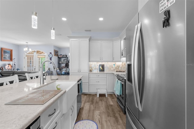 2911 Riverside Dr, Punta Gorda, FL 33950 - kitchen featuring appliances with stainless steel finishes, light wood finished floors, white cabinets, pendant lighting, and decorative backsplash
