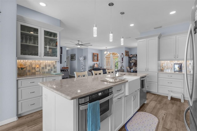 2911 Riverside Dr, Punta Gorda, FL 33950 - kitchen with appliances with stainless steel finishes, backsplash, an island with sink, light wood-type flooring, and white cabinets