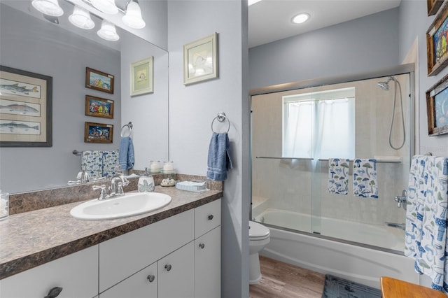 2911 Riverside Dr, Punta Gorda, FL 33950 - full bathroom featuring toilet, bath / shower combo with glass door, wood finished floors, and vanity