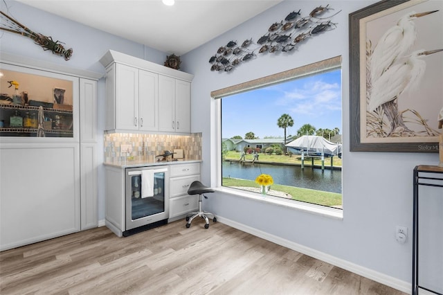 2911 Riverside Dr, Punta Gorda, FL 33950 - bar area with beverage cooler, a water view, light wood-style floors, backsplash, and baseboards